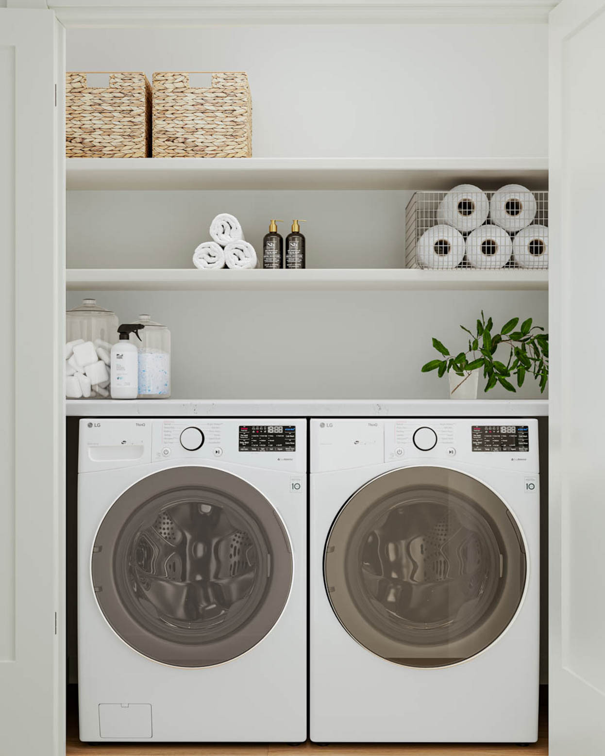 Kin & Kith – Laundry closet equipped with side-by-side white front-loading washer and dryer, upper shelving, and storage baskets.